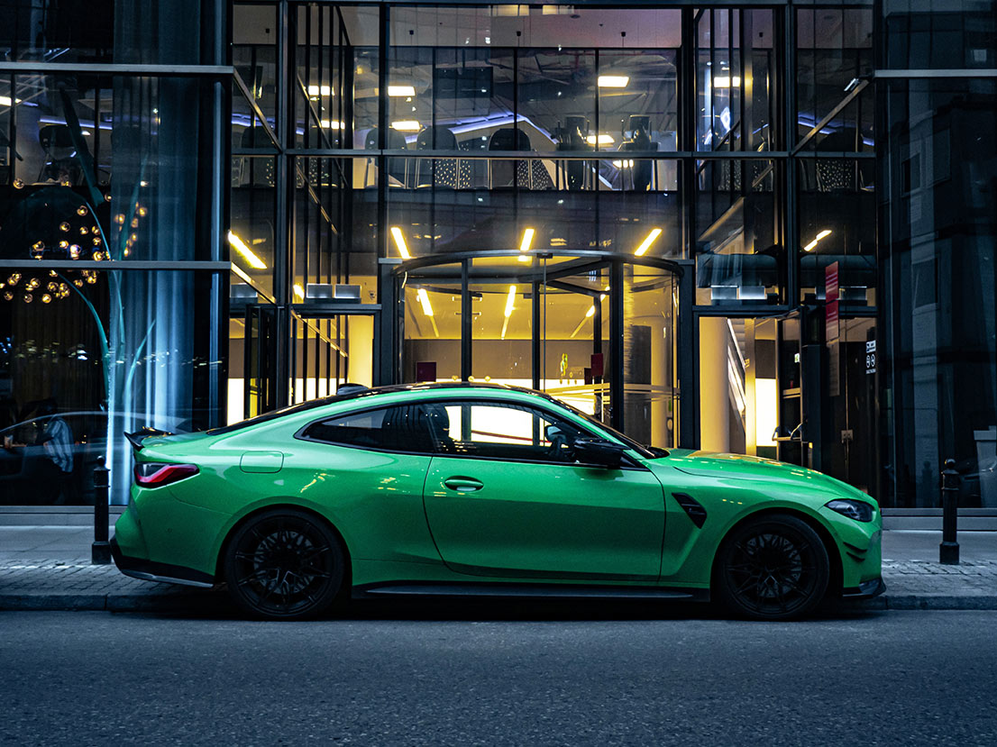 green-bmw-m4-parked-glass-building-night